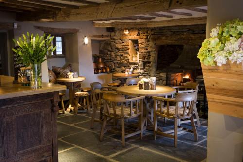 a restaurant with wooden tables and chairs and a stone wall at The Queen's Head Hotel in Troutbeck