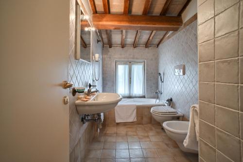 a bathroom with two sinks and a tub and a toilet at Country House La Padronale Del Rivo in Rivotorto