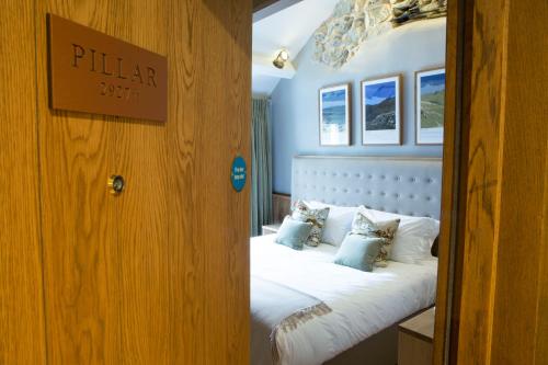 a bedroom with a bed with white sheets and pillows at The Queen's Head Hotel in Troutbeck