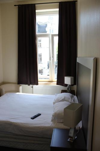 a bedroom with a bed with a remote control on it at Hotel Sansa in Maastricht