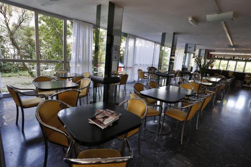 un restaurante con mesas, sillas y ventanas en Hotel Rondinella en Cesenatico