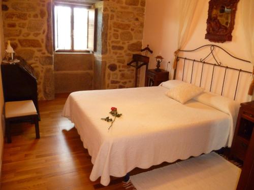 a bedroom with a white bed with a flower on it at Casal de Cereixo in Tufiones