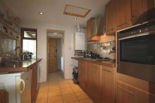 a large kitchen with wooden cabinets and a microwave at Wales' Highest Village - The Chartist Cottage - Trefil in Tredegar