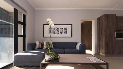 a living room with a blue couch and a coffee table at Odyssey Luxury Apartments - Back Up Generator in Johannesburg