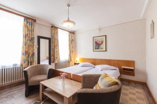 a hotel room with a bed and a table and chairs at Hotel DeFive in Berdorf