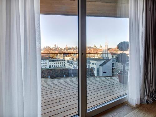 a view of a city from a balcony with sliding glass doors at Hotel Anker Luzern in Luzern