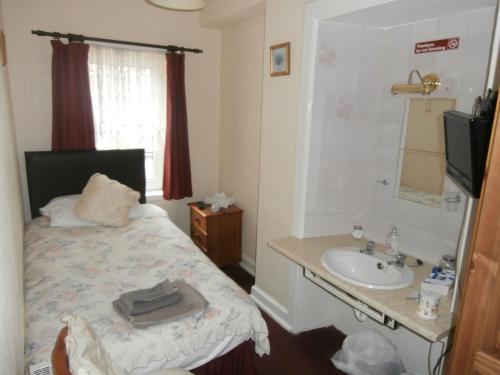 een kleine slaapkamer met een bed en een wastafel bij Monorene Guest House in Galashiels