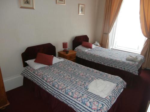 a hotel room with two beds and a window at Monorene Guest House in Galashiels
