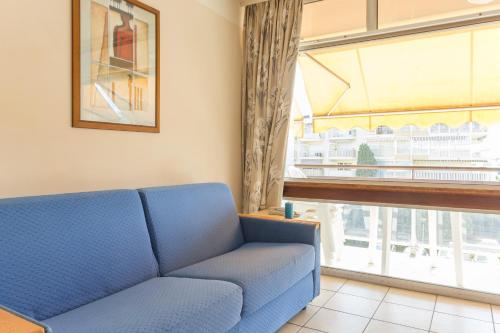 サン・ローラン・デュ・ヴァールにあるRésidence Héliotel Marineの窓付きの客室で、青いソファが備わります。