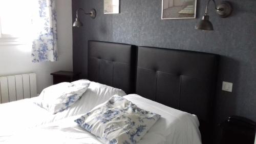 a bed with two pillows on it in a bedroom at Logis Hôtel Les Airelles Neufchâtel En Bray in Neufchâtel-en-Bray