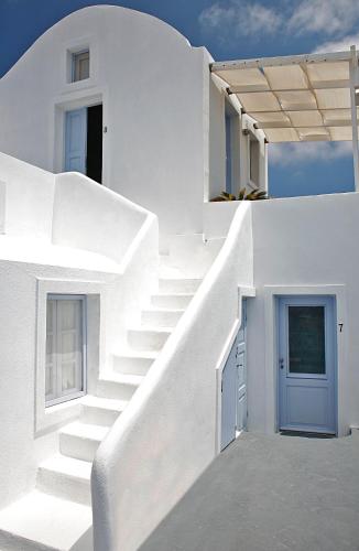 a white house with a blue door and stairs at Armeni Village in Oia