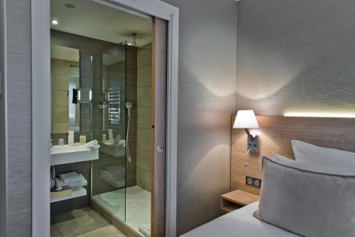 - une chambre avec une douche et un lit avec un miroir dans l'établissement Golden Tulip Sophia Antipolis - Hotel & Spa, à Valbonne