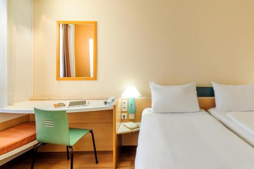 a hotel room with a bed and a desk at ibis Augsburg Hauptbahnhof in Augsburg