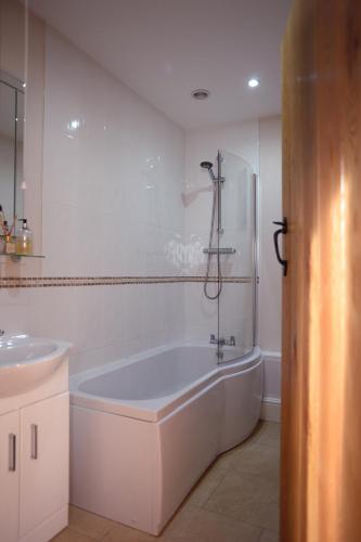a white bathroom with a tub and a sink at The Red Lion, Barn Accommodation in Thornby
