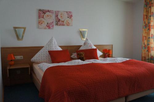 a bedroom with a red bed with a teddy bear on it at Gasthof zur Post in Neunkirchen am Brand