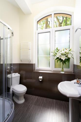 a bathroom with a toilet and a sink and a window at Modlin Palace in Nowy Dwór Mazowiecki