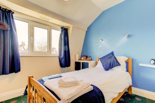 a bedroom with a bed with blue walls and windows at Rose-Dene in Scarborough