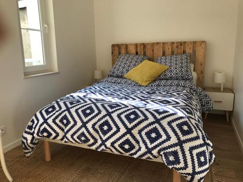 a bedroom with a bed with a blue and white comforter at Le Petit Nid d'Honfleur in Honfleur