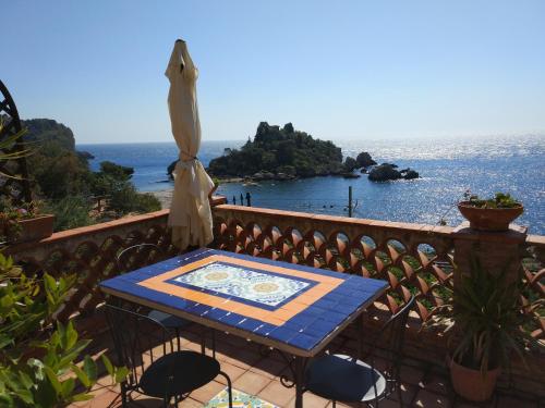 a table on a balcony with the view of the ocean at Isola Bella - Rooms il Pescatore in Taormina