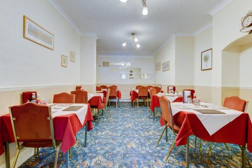 a dining room with tables and chairs with red tablecloths at Rose-Dene in Scarborough