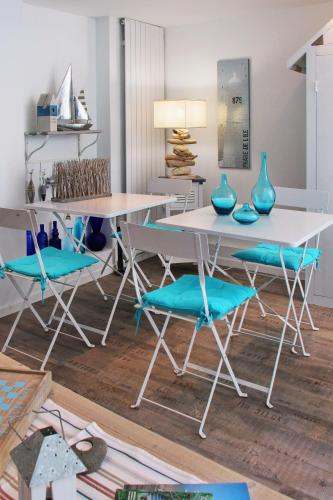 une salle à manger avec une table blanche et des chaises bleues dans l'établissement La Maison au-dessus des Voiles, à La Baule