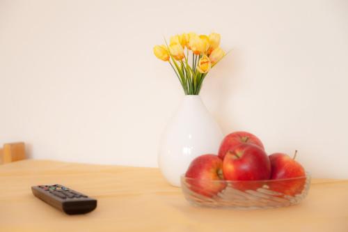 a bowl of apples and a vase with flowers at Hotel Gasthof Metzgerei Lamm - Benedikt Rückel in Geiselwind