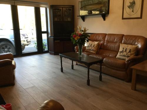 a living room with a brown leather couch and a table at Ryan's River Lodge B&B in Cong