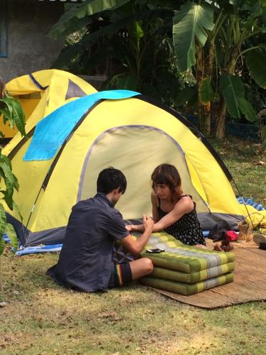 a man and woman sitting in front of a tent at Chiang Dao Story Camp in Chiang Dao