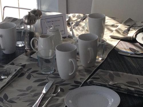 a table with white cups and plates on a table at Les Chalets Baie Cascouia in Lac Kénogami
