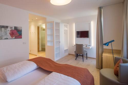 a bedroom with a bed and a desk in a room at Garni Hotel Kessler in Tirolo