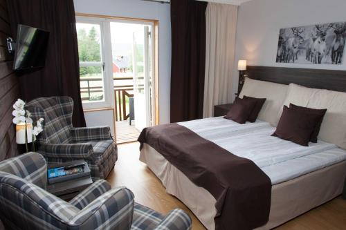 a bedroom with a bed and two chairs and a window at Eriksgårdens Fjällhotell in Funäsdalen