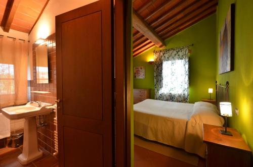 ein Badezimmer mit einem Schlafzimmer mit einem Bett und einem Waschbecken in der Unterkunft Poggio Cennina Resort in Bucine