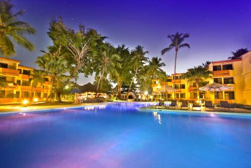 a large swimming pool with palm trees and buildings at Viva Dominicus Beach by Wyndham, A Trademark All Inclusive in Bayahibe