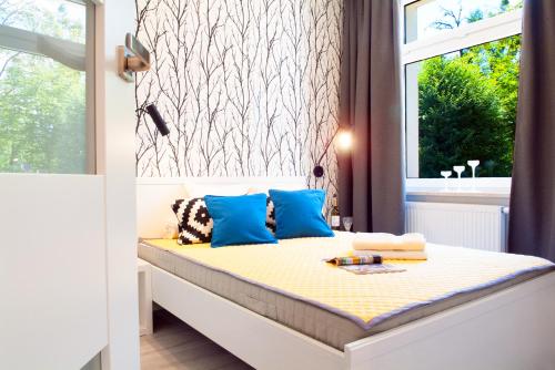 sypialnia z łóżkiem z niebieskimi poduszkami i oknem w obiekcie Apartament 4 You w Grudziądzu