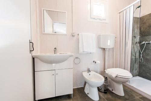 uma casa de banho branca com um lavatório e um WC em Real Village Roma em Roma