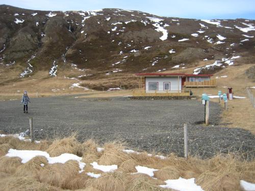 a person standing in a field in front of a house at Ásbrandsstadir Cottages in Vopnafjörður
