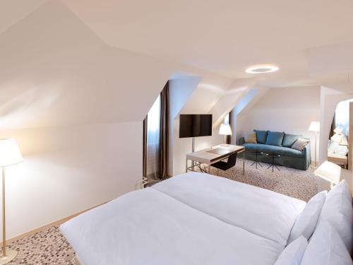 ein Schlafzimmer mit einem weißen Bett und einem Sofa in der Unterkunft Hotel Savoy in Bern