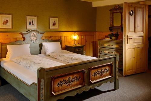 a bedroom with a large bed with a dresser and a mirror at Baeren Hotel, The Bear Inn in Wilderswil
