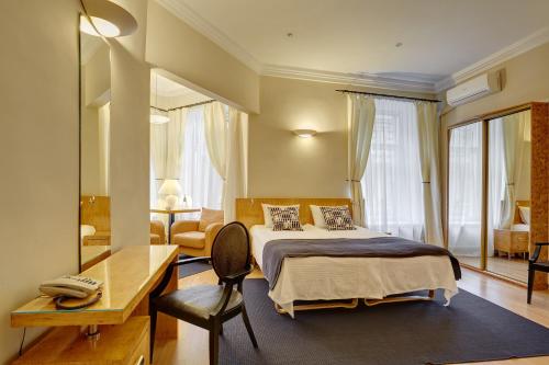 1 dormitorio con cama, escritorio y silla en Anichkov Pension, en San Petersburgo