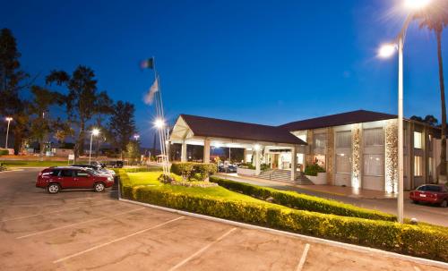 a building with a car parked in a parking lot at Hotel Las Trojes in Aguascalientes