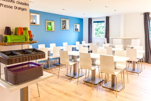 Cette chambre est dotée de tables et de chaises blanches ainsi que d'un mur bleu. dans l'établissement ibis Styles Toulouse Nord Sesquieres, à Toulouse