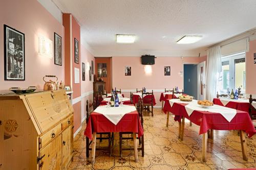 アオスタにあるアルベルゴ マンクーゾ デル ヴォイゾンの赤いテーブルクロスのテーブルが並ぶレストラン