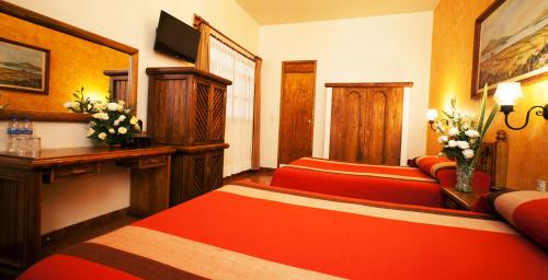 Habitación de hotel con 2 camas y escritorio con flores en Gran Hotel Pátzcuaro, en Pátzcuaro