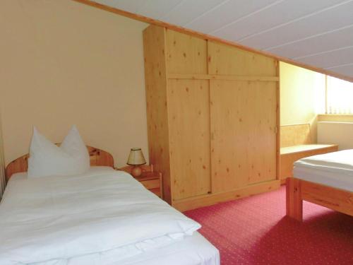 a bedroom with a white bed and a wooden cabinet at Pleasant Holiday Home With Terrace in Schirgiswalde Germany in Schirgiswalde