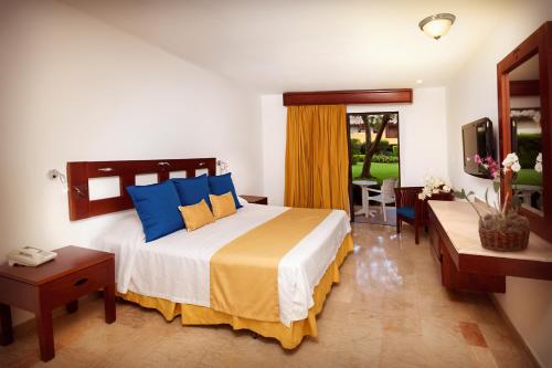 a bedroom with a large bed with blue and yellow pillows at Viva Dominicus Palace by Wyndham, A Trademark All Inclusive in Bayahibe