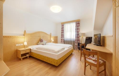 a bedroom with a bed and a desk with a computer at Parkhotel Post in Chiusa