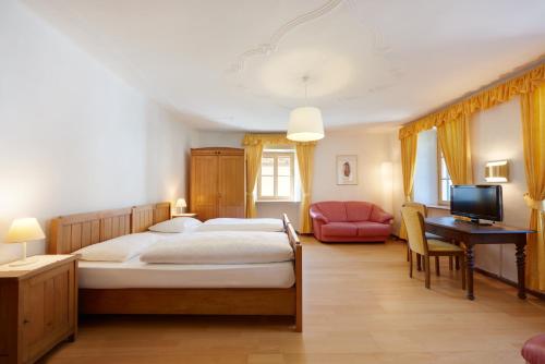 a bedroom with a bed and a desk and a television at Parkhotel Post in Chiusa