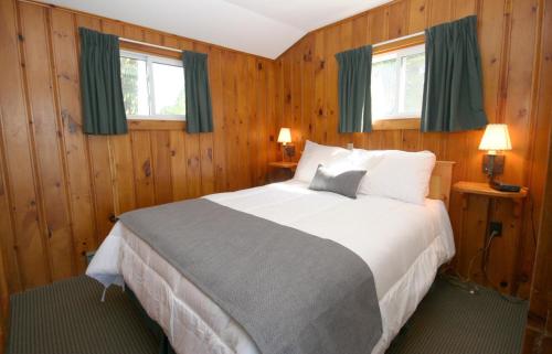 a bedroom with a large bed with green curtains at Elmhirst's Resort in Keene