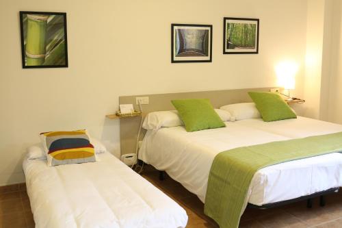 two beds with green pillows in a room at Apartamentos Turísticos Cancelas by Bossh Hotels in Santiago de Compostela