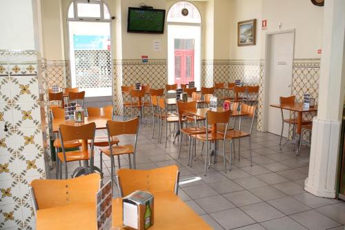 a dining room with tables and chairs and a tv at Hotel Alianca in Figueira da Foz